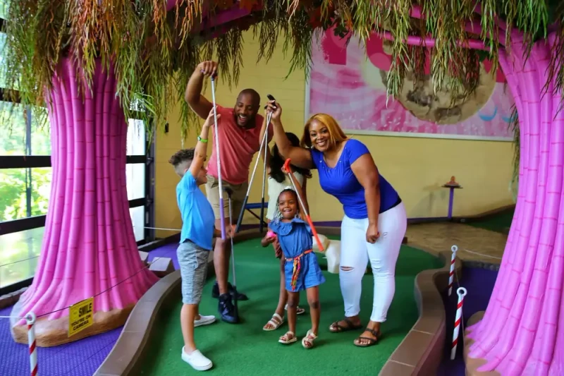 family of 5 playing on Crave Golf Club Indoor Mini Golf Course in Pigeon Forge TN